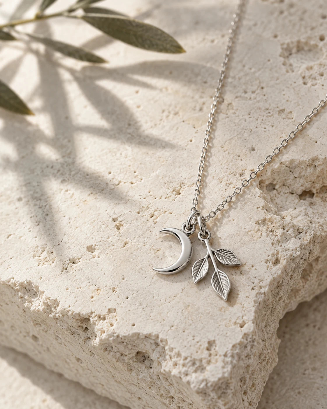 Silver crescent and leaf pendant on limestone